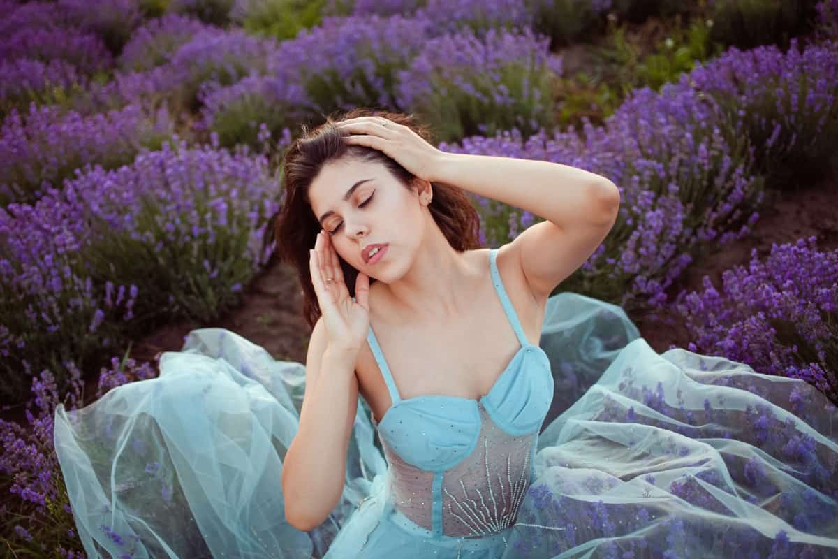 Fotograf kobiecy. Sesja w plenerze na polu lawendy. Kobieta w błękitnej sukni pozuje na tle fioletowych kwiatów. Zdjęcie ilustruje połączenie natury i delikatnej kobiecości w sesji zdjęciowej.