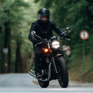 Mężczyzna w kasku na motocyklu; postać przedstawiona jako zadowolony klient, który poleca romantyczną sesję na walentynki jako idealny prezent.