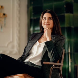Zadowolona klientka w eleganckim stroju biznesowym, siedząca w fotelu; postać symbolizująca profesjonalizm i satysfakcję z efektów sesji zdjęciowej dla par.