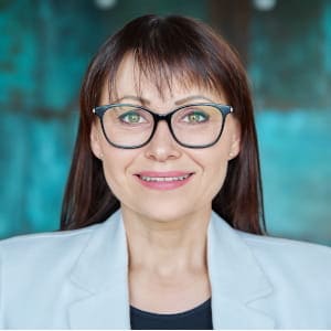 Uśmiechnięta kobieta w okularach i jasnej marynarce; portret zadowolonej klientki przy tekście o swobodnej atmosferze podczas sesji dla par.