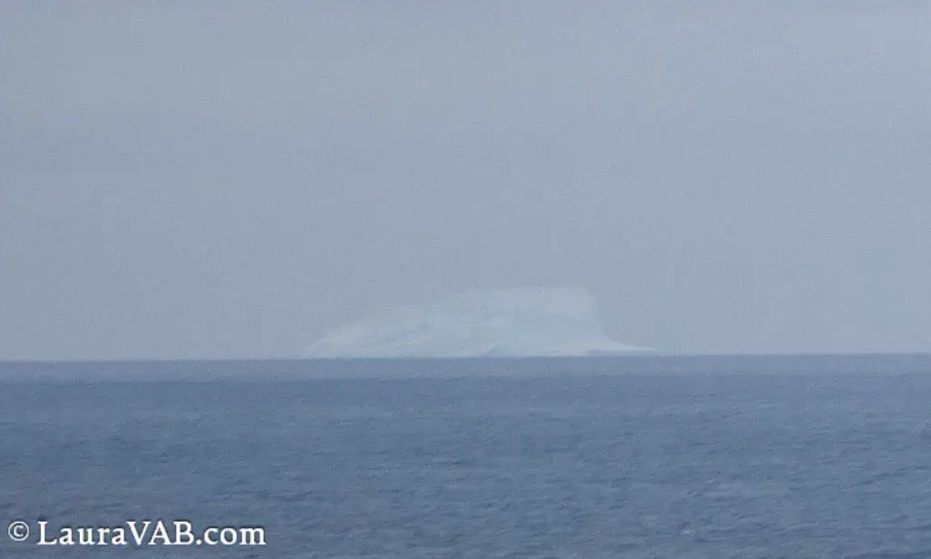 Iceberg faint against sea and sky