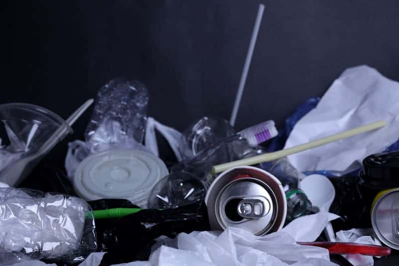 A heap of plastic bottles and other waste on a black background after rubbish removal.