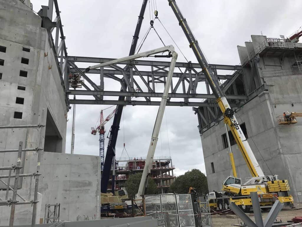 L’arche de la MECA prend forme ! Pose de la poutre métallique qui relie les deux piliers du bâtiment.