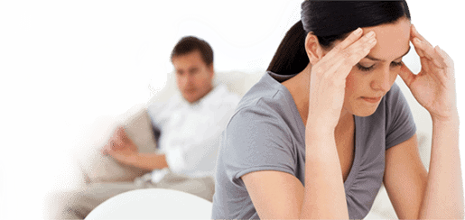 A man and woman sitting on a couch experiencing Body Stress Release with their hands on their heads.
