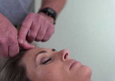 A woman receiving a Body Stress Release on her head.