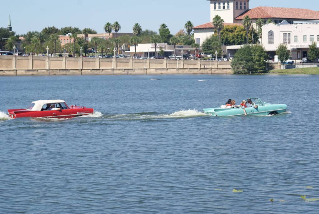 Two Amphicars driving across Lake Mirror during the Lake Mirror Classic