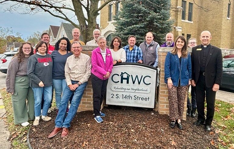 A group of smiling and people standing around a sign that says "CHWC".