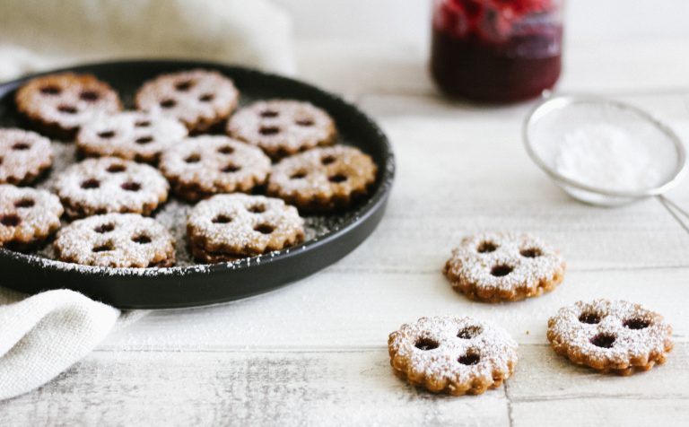 Auf dem Bild sind glutenfreie, gesunde Linzeraugen zu sehen, die aus Hafermehl, Buchweizenmehl, Mandeln und warmen Gewürzen zubereitet wurden. Die Kekse sind mit einer zuckerarmen Marmelade gefüllt und eignen sich perfekt für eine bekömmliche, nährende Weihnachtsbäckerei. Durch ihre TCM-Wirkung stärken sie die Mitte, wärmen und beruhigen.