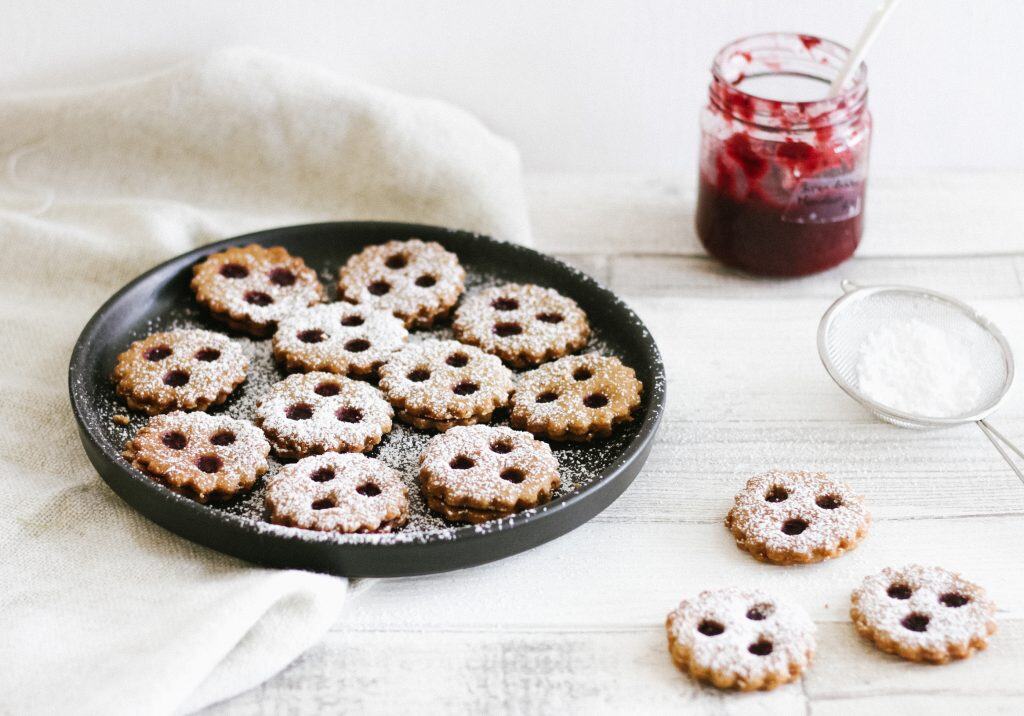 Auf dem Bild sind glutenfreie, gesunde Linzeraugen zu sehen, die aus Hafermehl, Buchweizenmehl, Mandeln und warmen Gewürzen zubereitet wurden. Die Kekse sind mit einer zuckerarmen Marmelade gefüllt und eignen sich perfekt für eine bekömmliche, nährende Weihnachtsbäckerei. Durch ihre TCM-Wirkung stärken sie die Mitte, wärmen und beruhigen.