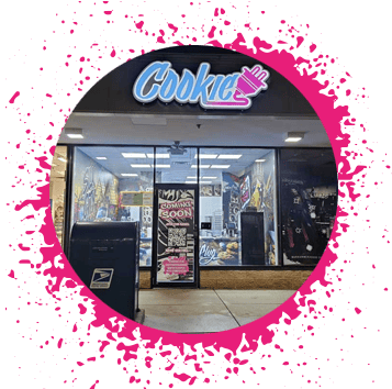 Storefront at night that has a lit up sign that says 'Cookie' with an electrical plug in graffiti typograghy with a sing that says 'Coming Soon'