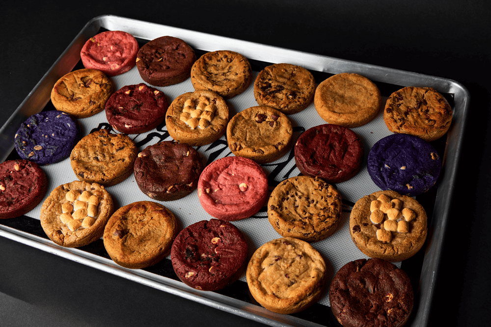 large baking tray with cookies of all types like chocolate chip cookies, strawberry cookies, peanut butter cookies, and chocolate cookies.