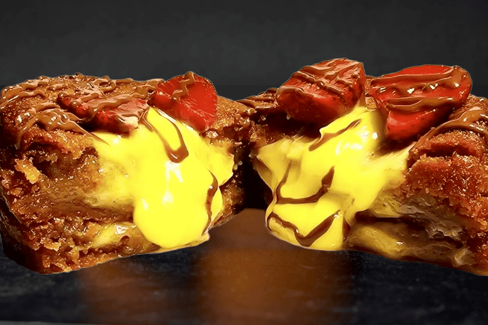 A thick stuffed cookie with a custard filling, drizzled chocolate, and sliced strawberries