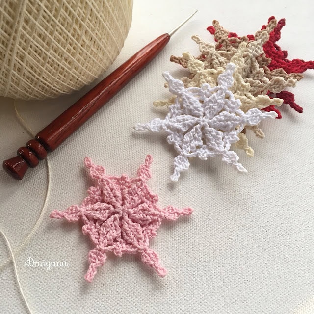 An intricate Frostwoven crochet snowflake pattern by Draigunna, featuring a lace-like design perfect for elegant winter projects.