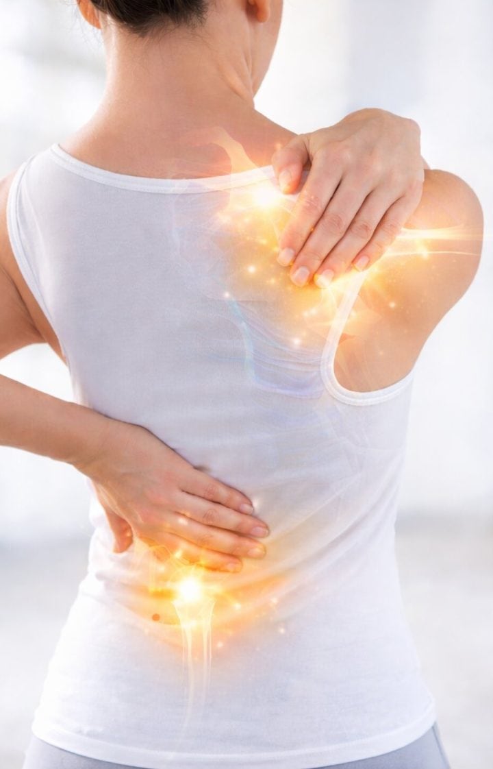 A woman in a white tank top holds her upper back and lower back, with glowing light effects highlighting areas of discomfort.