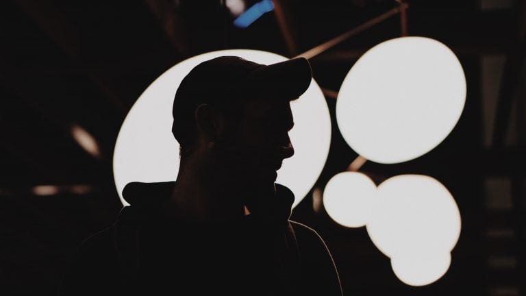 Silouette of man in cap wearing headphones