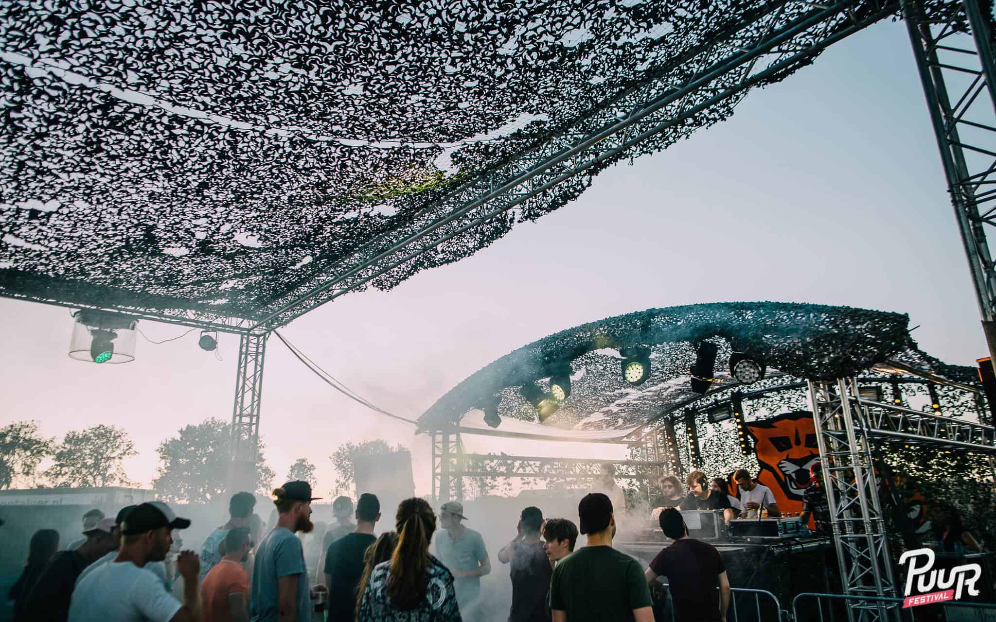 `Legergroene camouflagenetten over festivalterrein gespannen