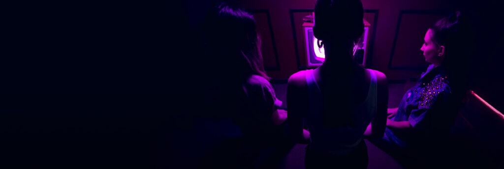 Two people are sitting in a dark room with purple lights.