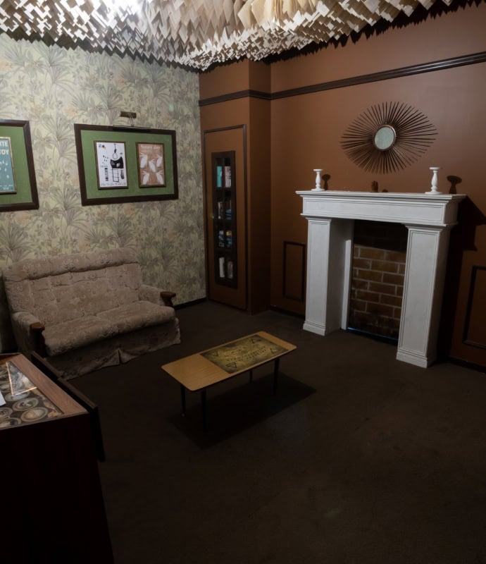 A room with a couch, fireplace and a table.