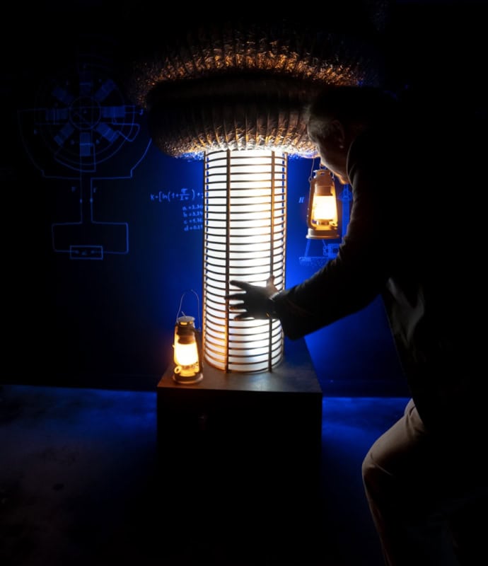 A man in a dark room with a light on top of a lamp.