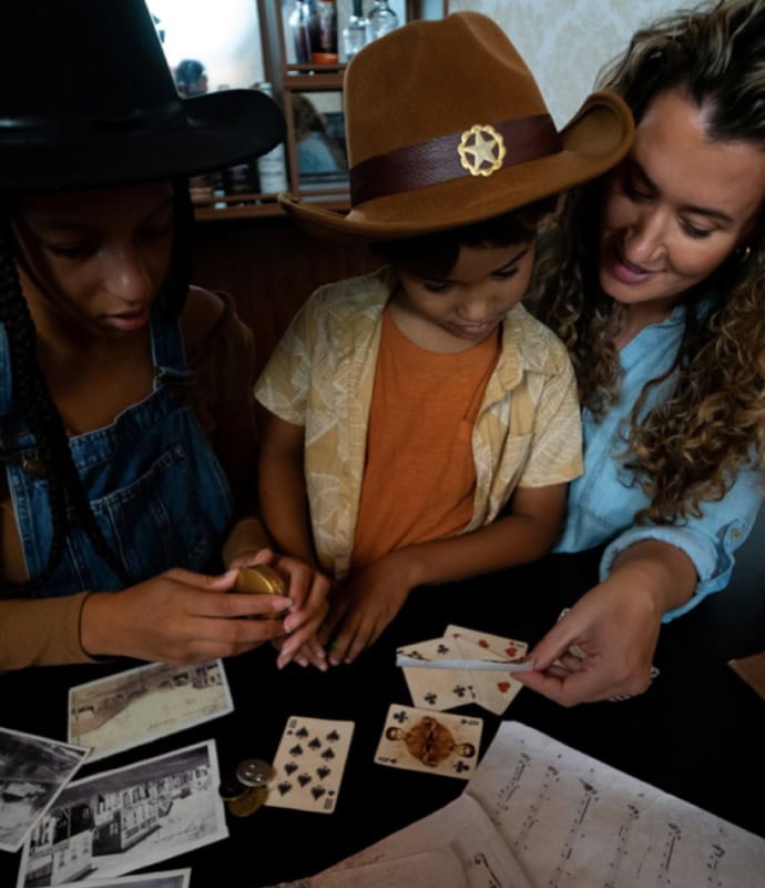 A woman and two children playing cards.