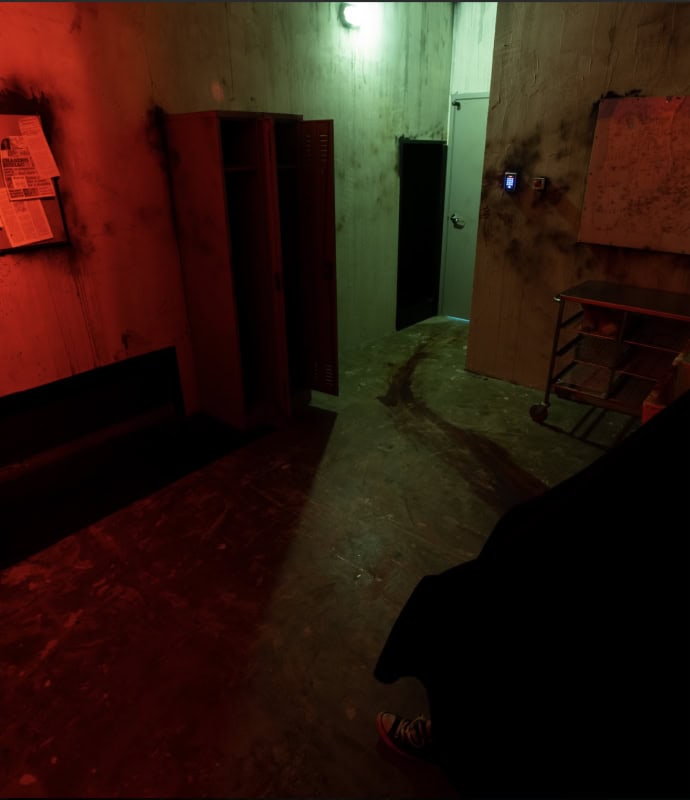 A dark room with a person sitting in the corner.