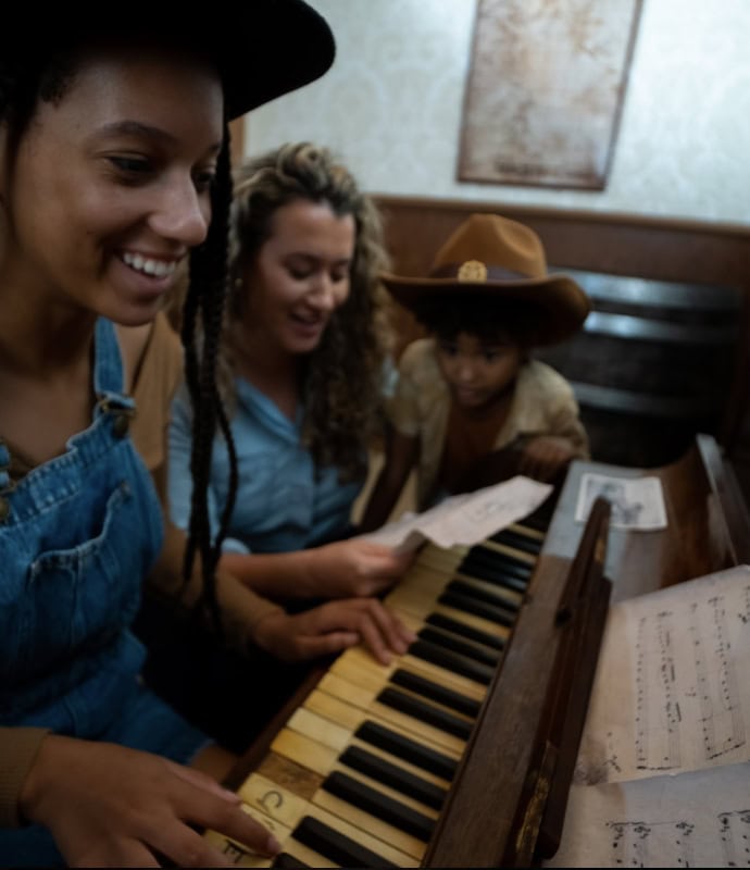 A woman and two children playing the piano.