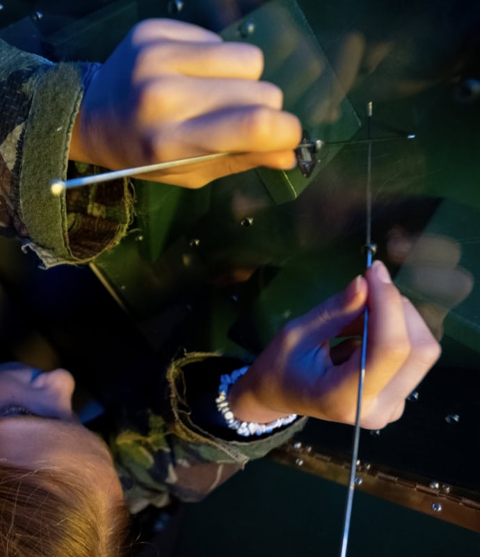 A person is using a pair of scissors to cut through a glass window.