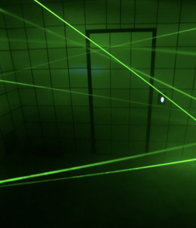A green laser is shining through a door in a dark room.