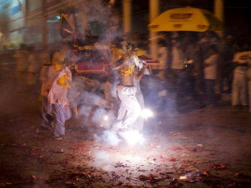 People having a parade on the street and stepping on some firecrackers