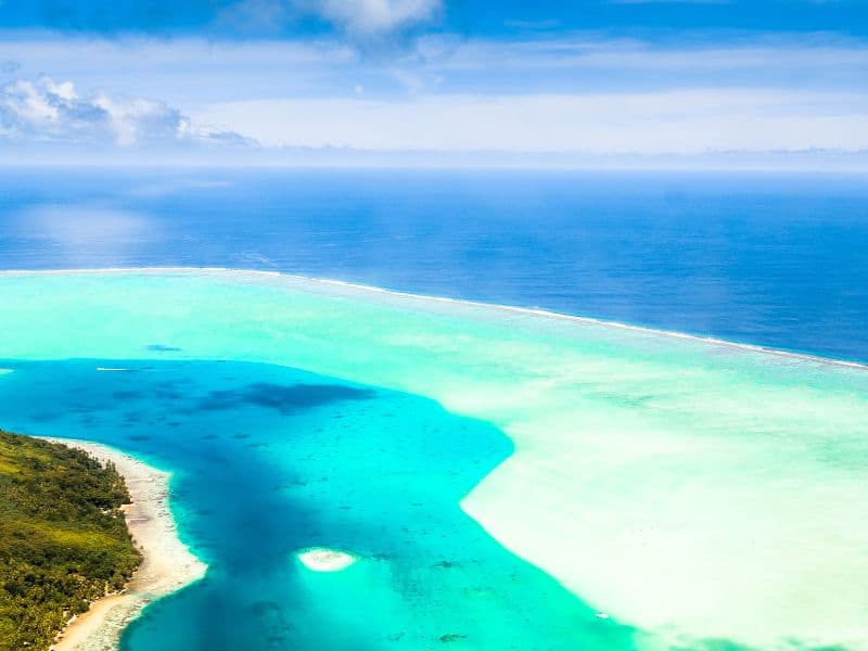 Aerial view of a tropical lagoons with clear cyan blue water in Bora Bora