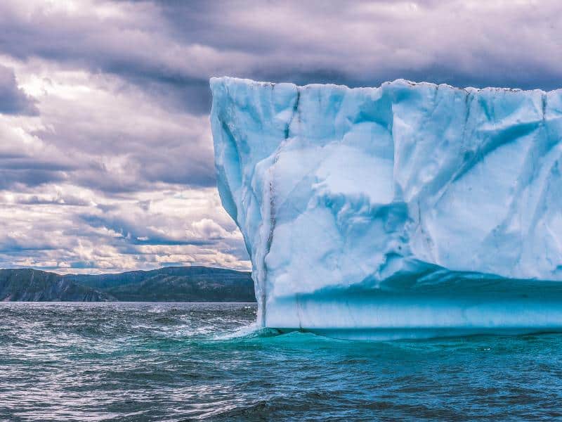 Detailed view of blue glacier ice face with dramatic structure against cloudy sky