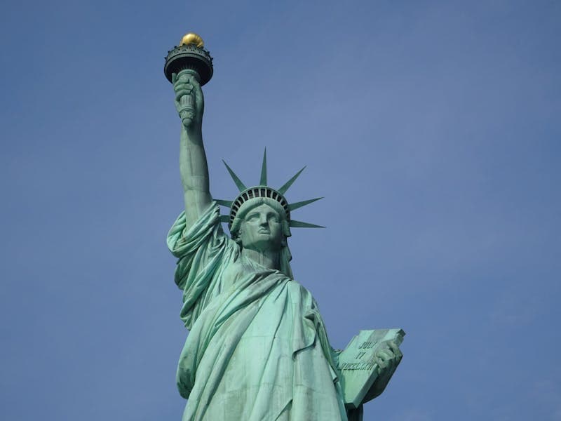 Iconic Statue of Liberty in New York with a vibrant blue sky backdrop, symbolizing freedom and hope.