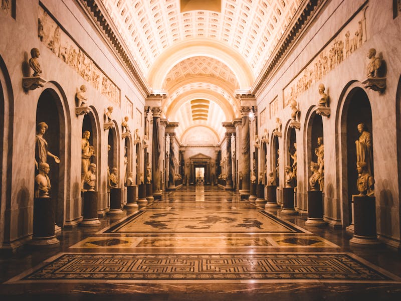 A stunning view of a hallway adorned with classical sculptures in the Vatican Museums.