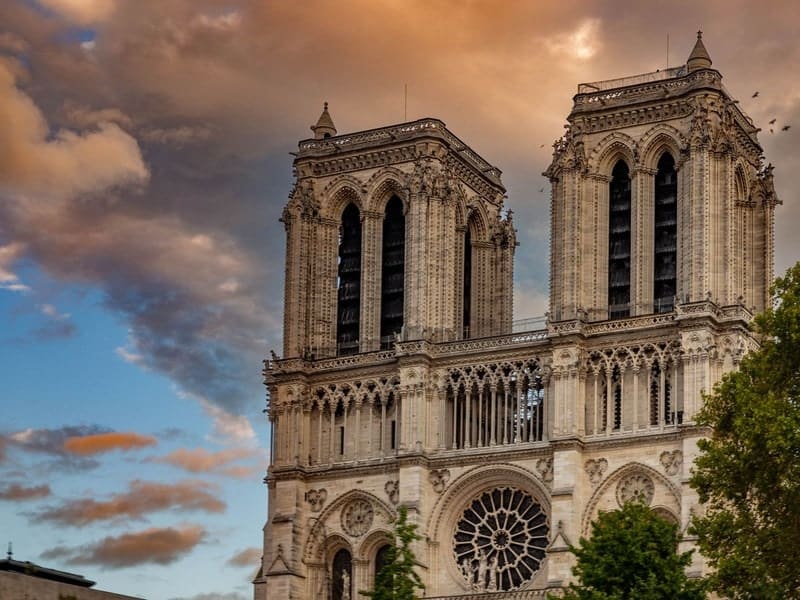 The iconic Notre-Dame Cathedral captured at sunset with dramatic skies in Paris.