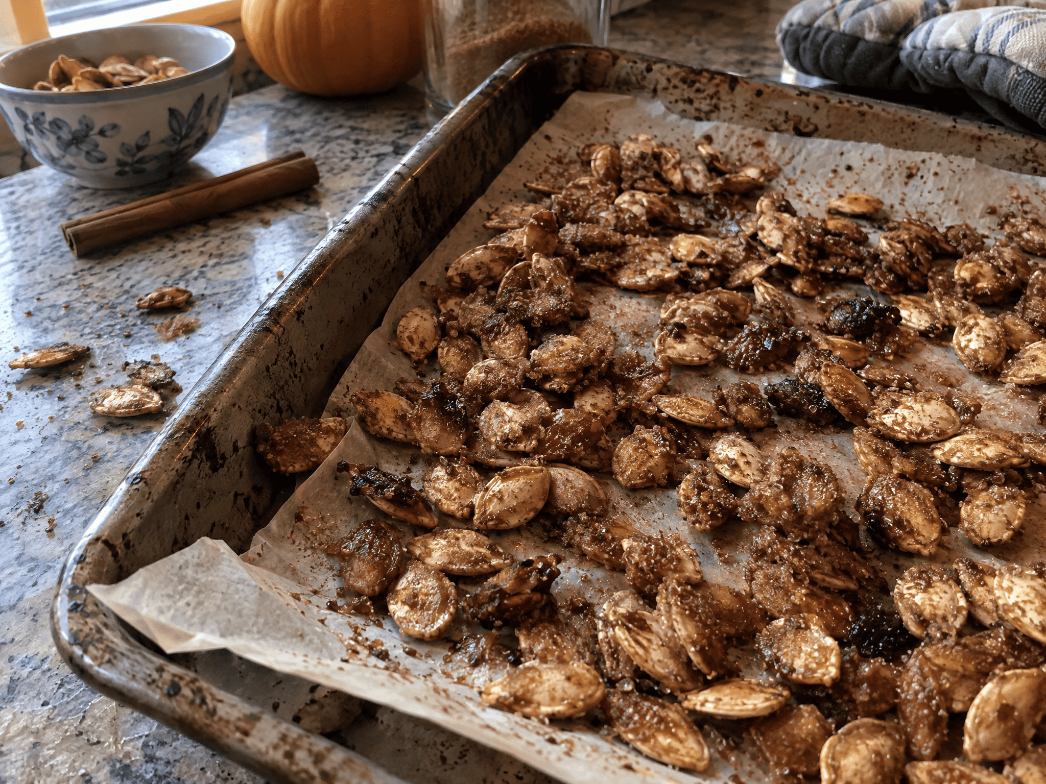 Close-up of glistening cinnamon sugar pumpkin seeds on a parchment-lined baking sheet fresh from the oven