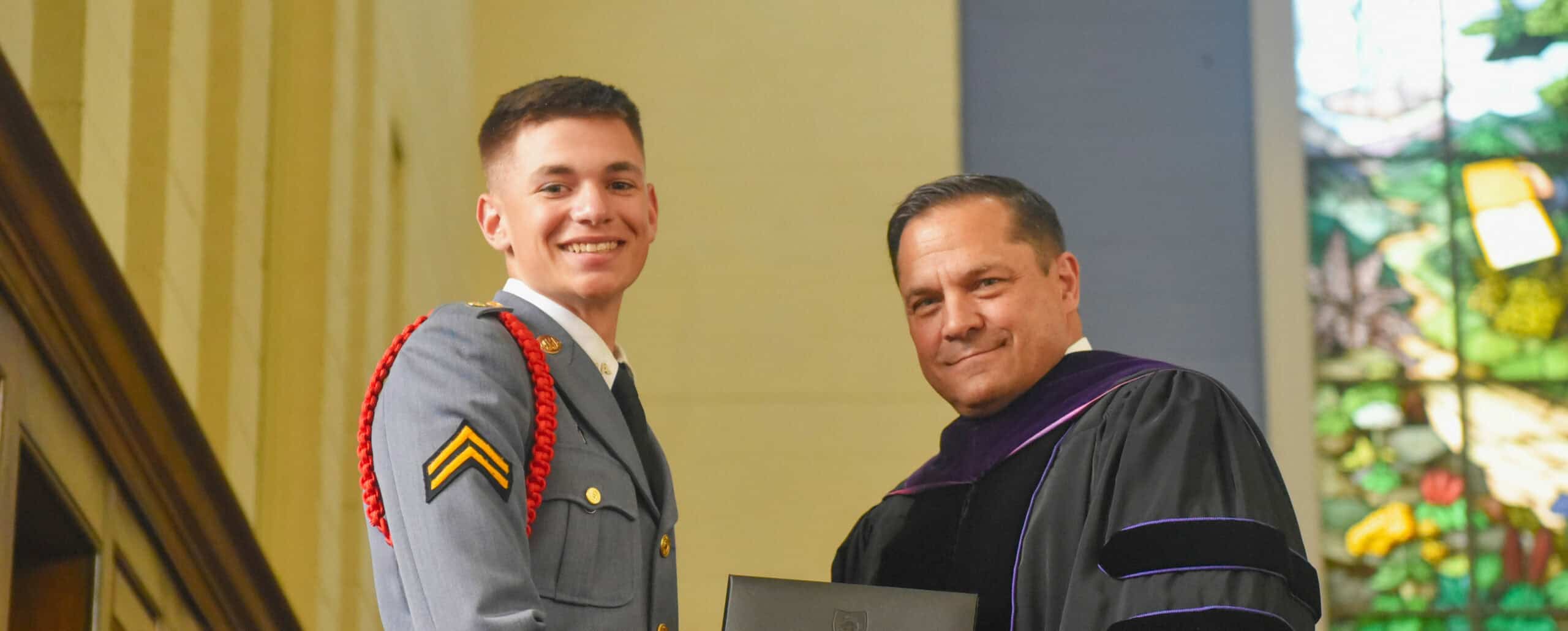 Cadet shaking hands with President while being handed diploma.