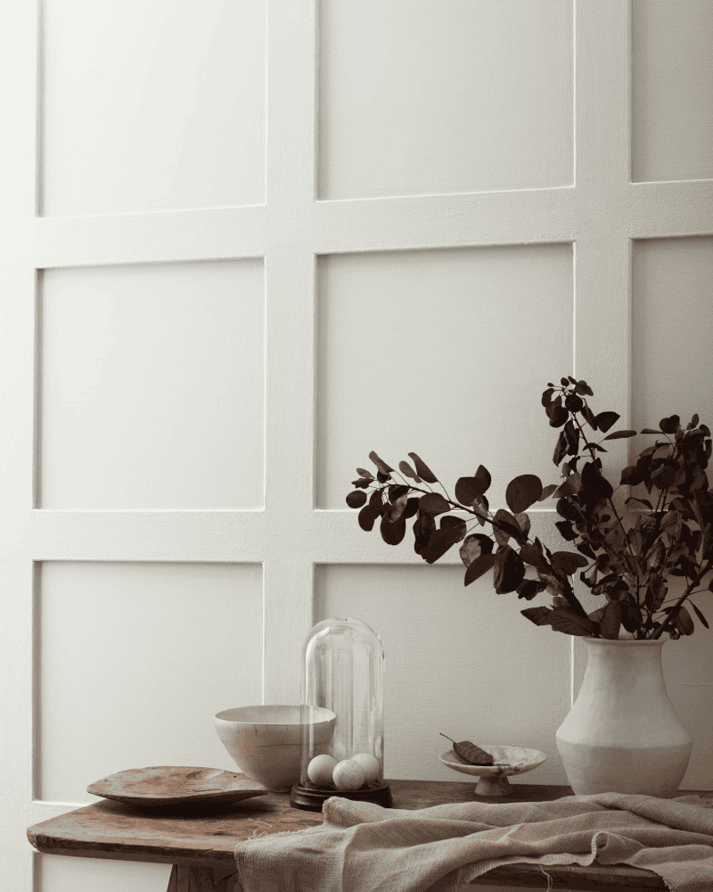 Headwaters_Benjamin_Moore_colour_of_the_year_2023_neutral_pairings_gray_owl wooden table and vase with flowers in front of a wall painted with Benjamin Moore Gray Owl colour