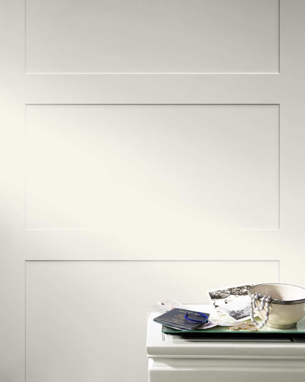 door-painted-white-dove paneled wall painted with benjamin moore white dove colour and small table in front.