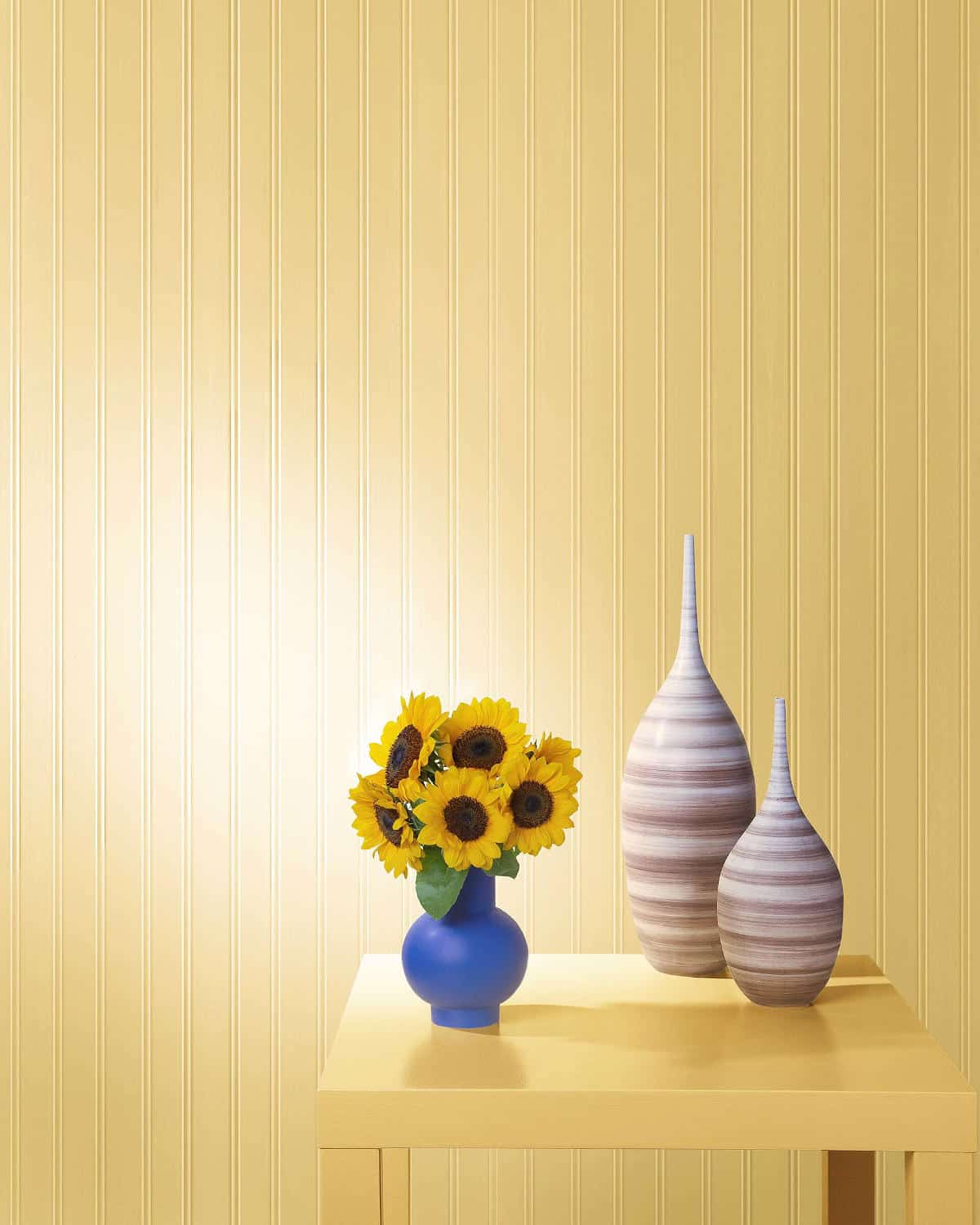 honeybee-colour-benjamin-moore a wall painted in benjamin moore's honebee colour with a table in front and a vase of miniature sunflowers