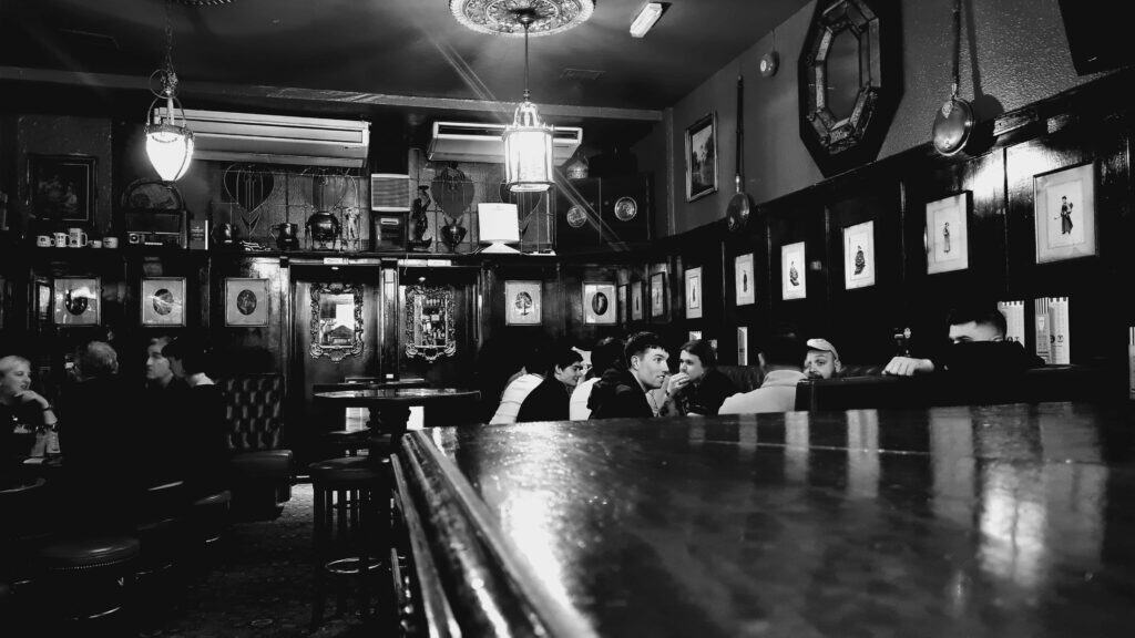 blanco y negro barra de madera y gente tomando cerveza detras