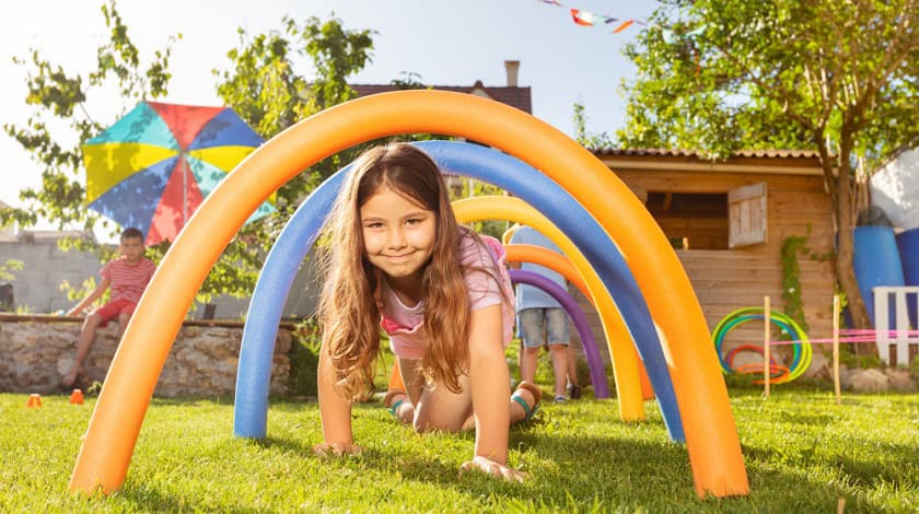 A chilc in the back yard crawling through hoops