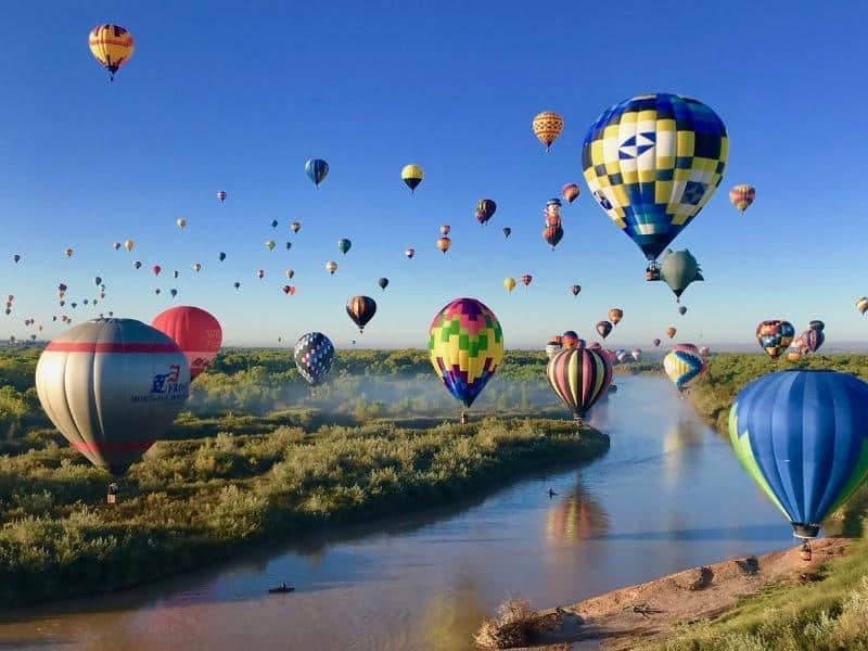 A whole bunch of hot air balloons in the sky above the Rio Grande river in New Mexico