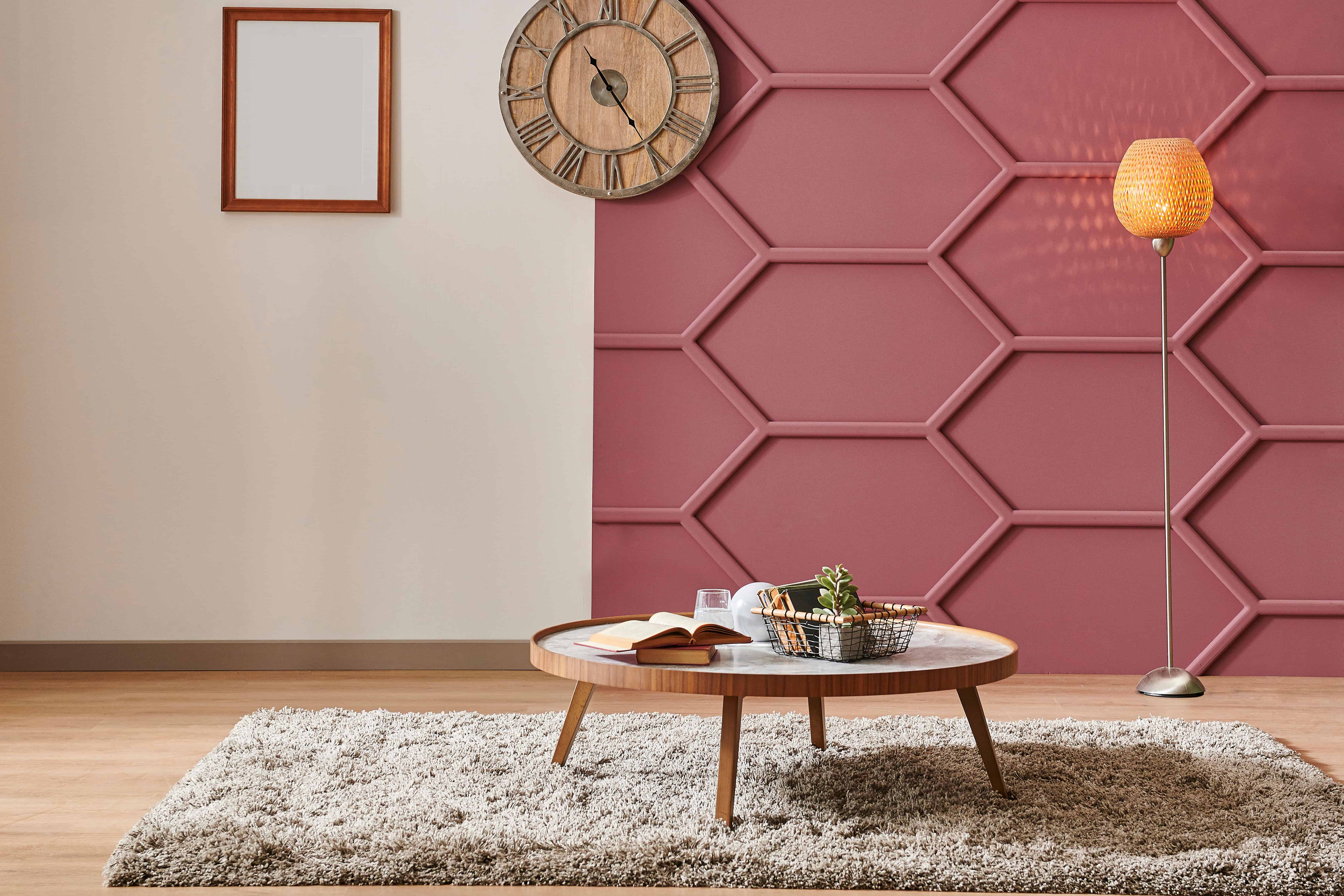 A claret-red textured accent wall wraps a living room corner, echoed by a brass-toned floor lamp beside a round wood table.