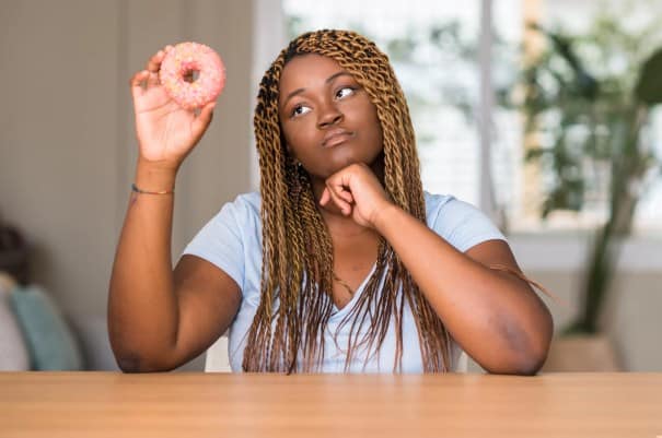 Young Black woman staring at donut