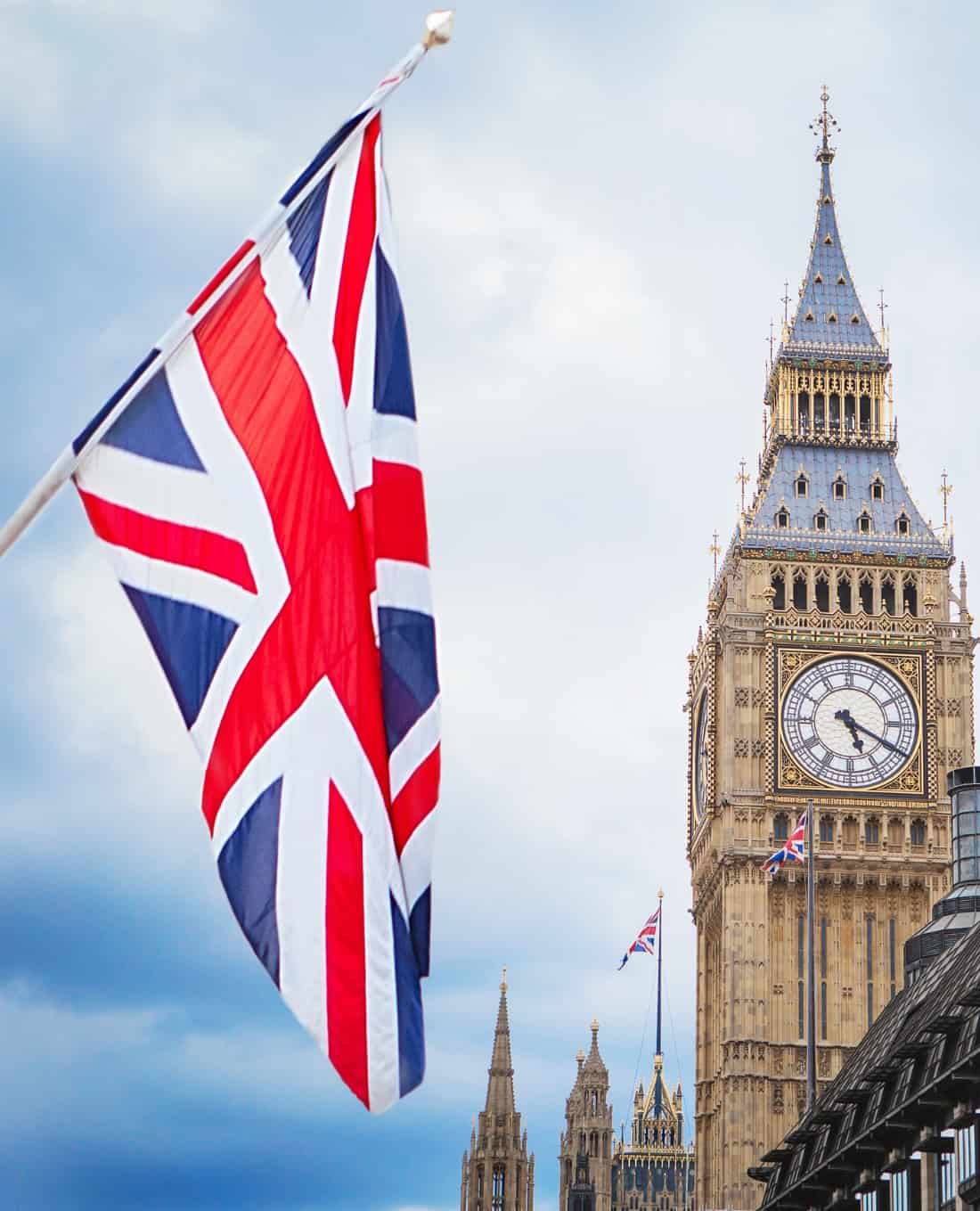 Union Jack flag flying in front of the Elizabeth Tower and Palace of Westminster in London, symbolizing UK governance and regulation.