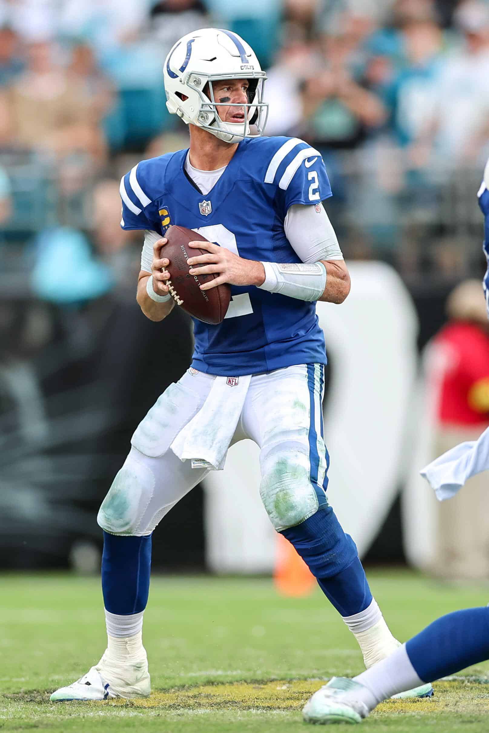 NFL quarterback in a blue uniform holding the football and preparing to throw during a game, representing the central role of American football in US sports betting.