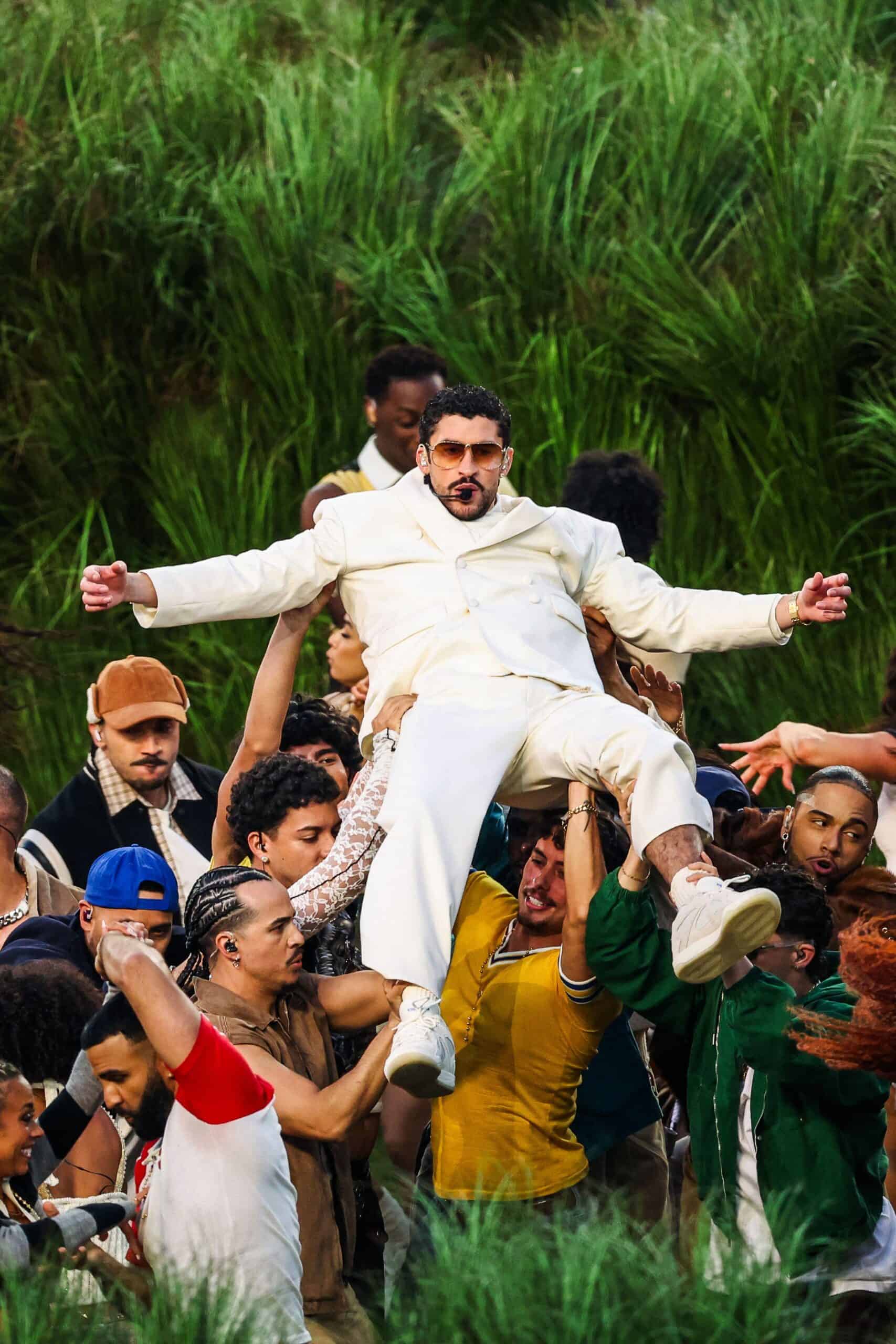 Performer Bad Bunny in a light‑coloured suit is held a loft by dancers in front of green grass during the Apple Music Halftime Show at Super Bowl LX at Levi’s Stadium in Santa Clara, California, on 8 February 2026.