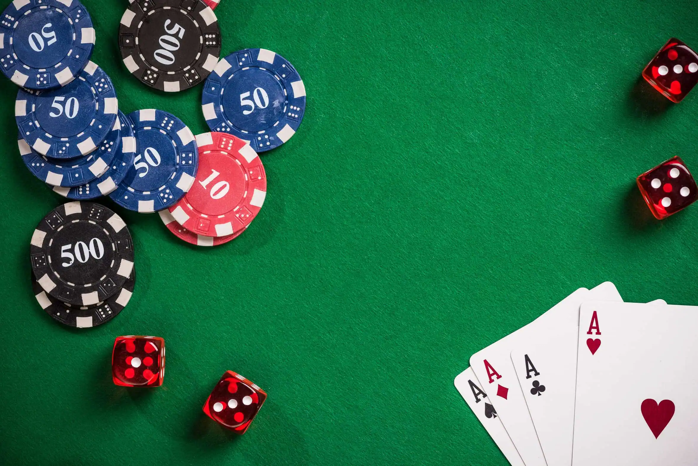 Casino chips, dice and playing cards arranged on green felt.