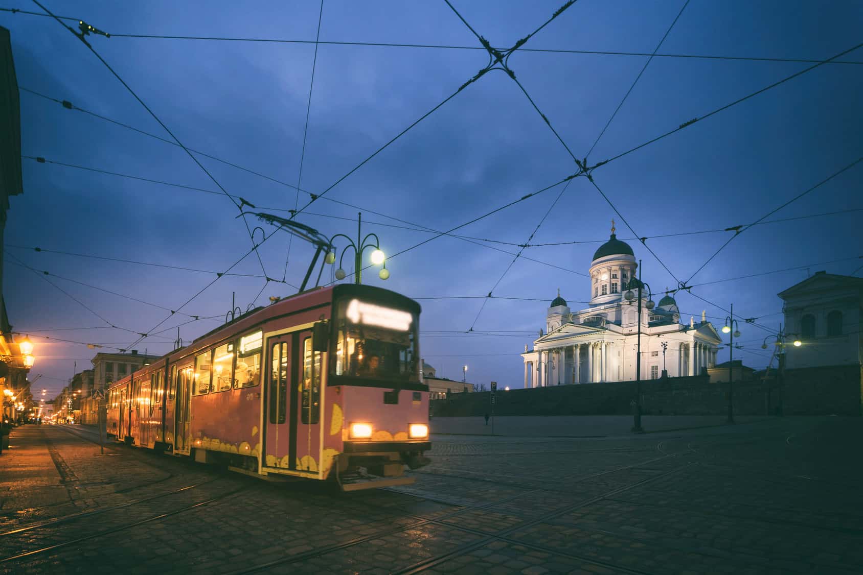 A tram passing Senate Square with Helsinki Cathedral behind it.