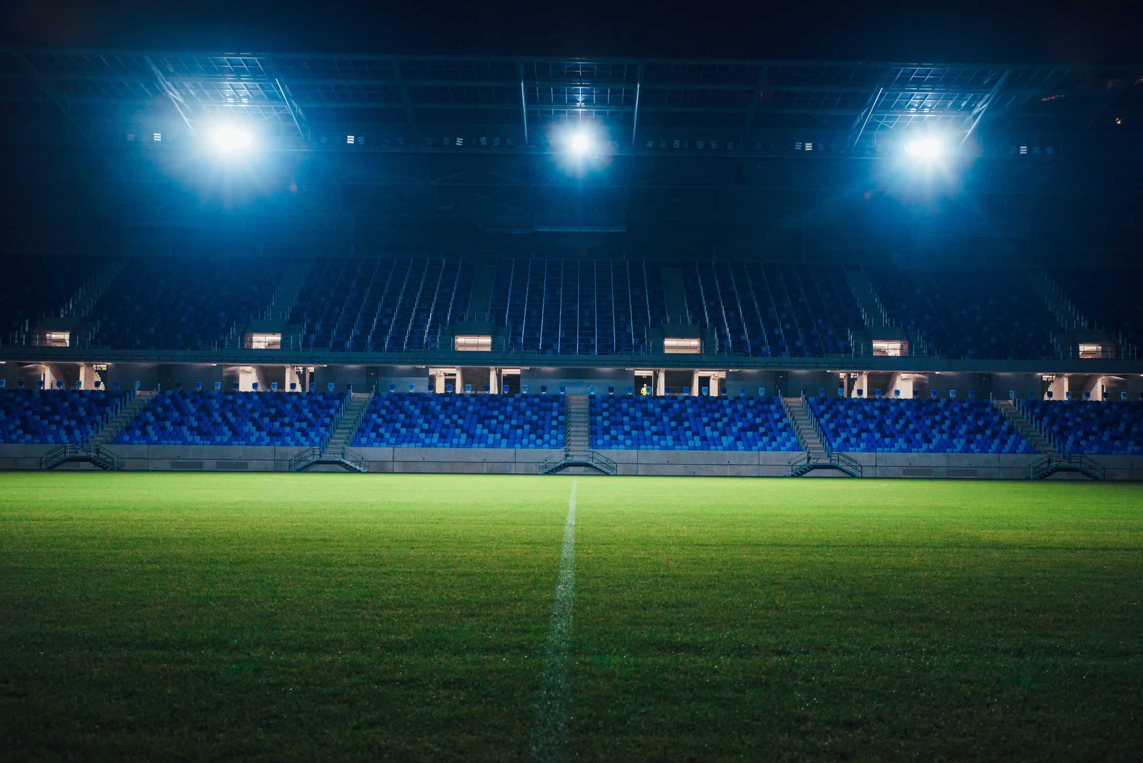 An empty football stadium under floodlights.